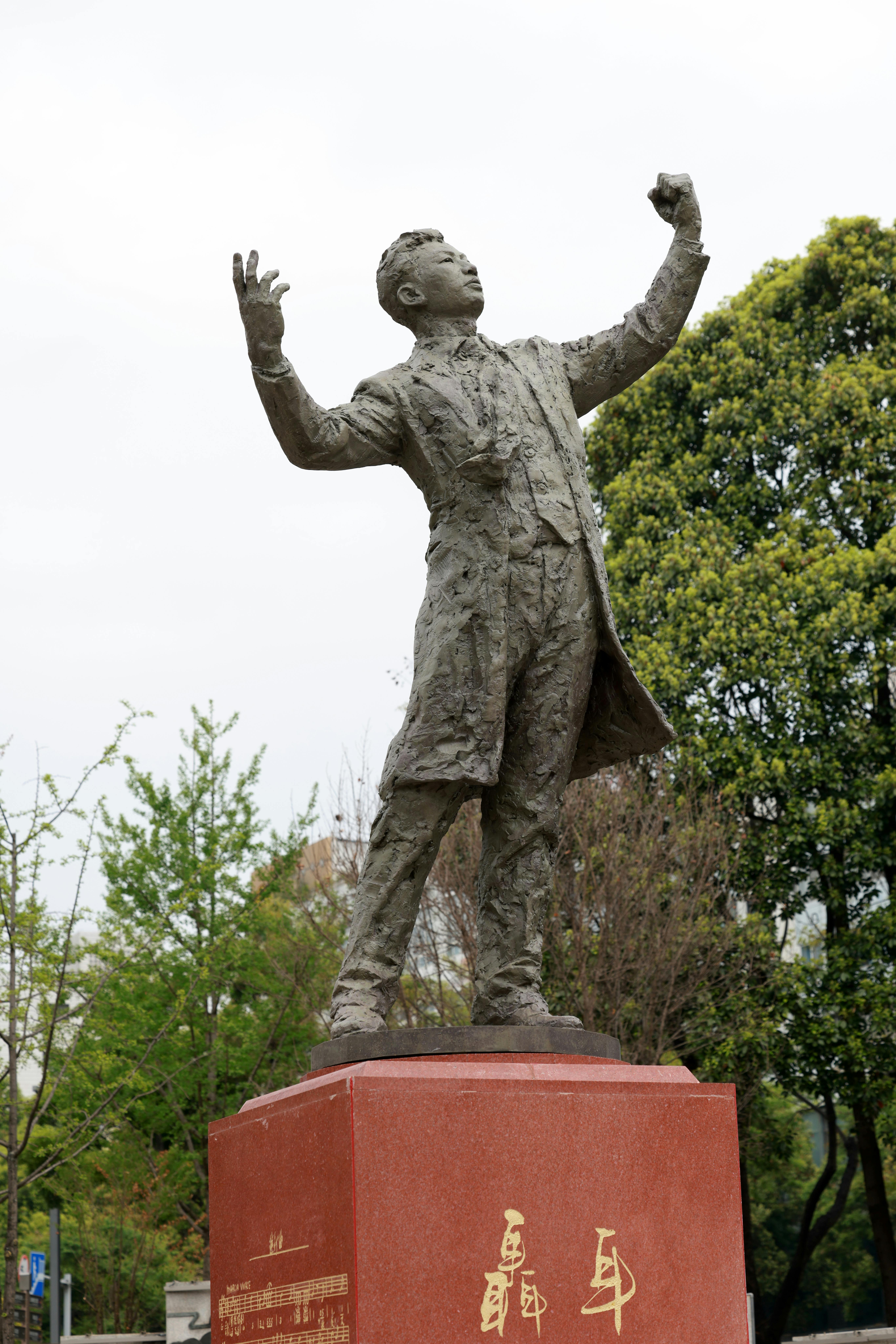 Statue of Man in Suit with Raised Arms Outdoors