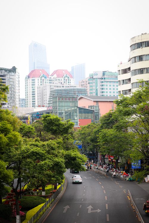 Free Vibrant cityscape featuring modern architecture, lush greenery, and urban life on a busy street. Stock Photo