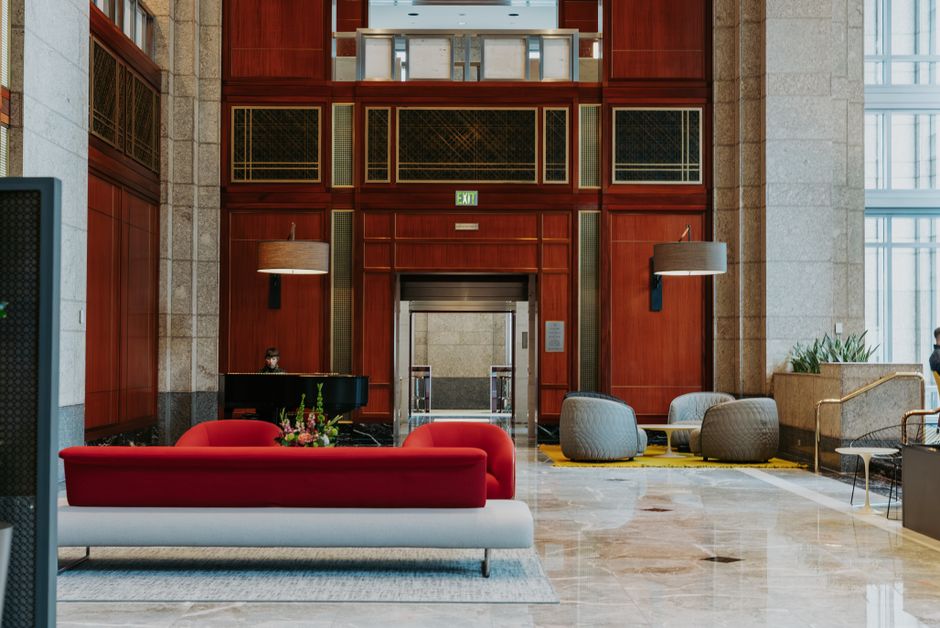 Spacious hotel lobby featuring modern furnishings, red sofa, and elegant architectural details.