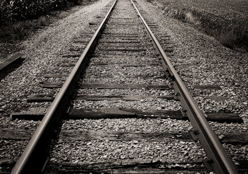 Black and white photo of rustic railroad tracks disappearing into the distance.