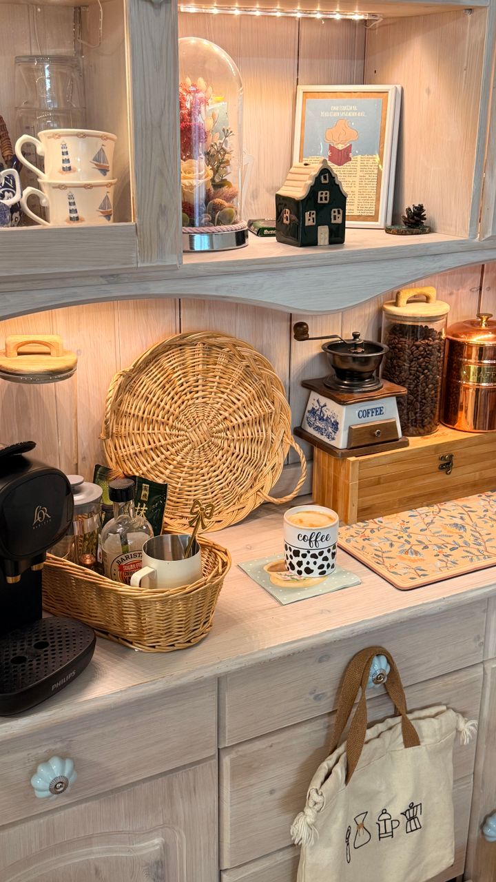 A built-in base cabinet coffee station with a pull-out shelf and mug hooks in a modern kitchen