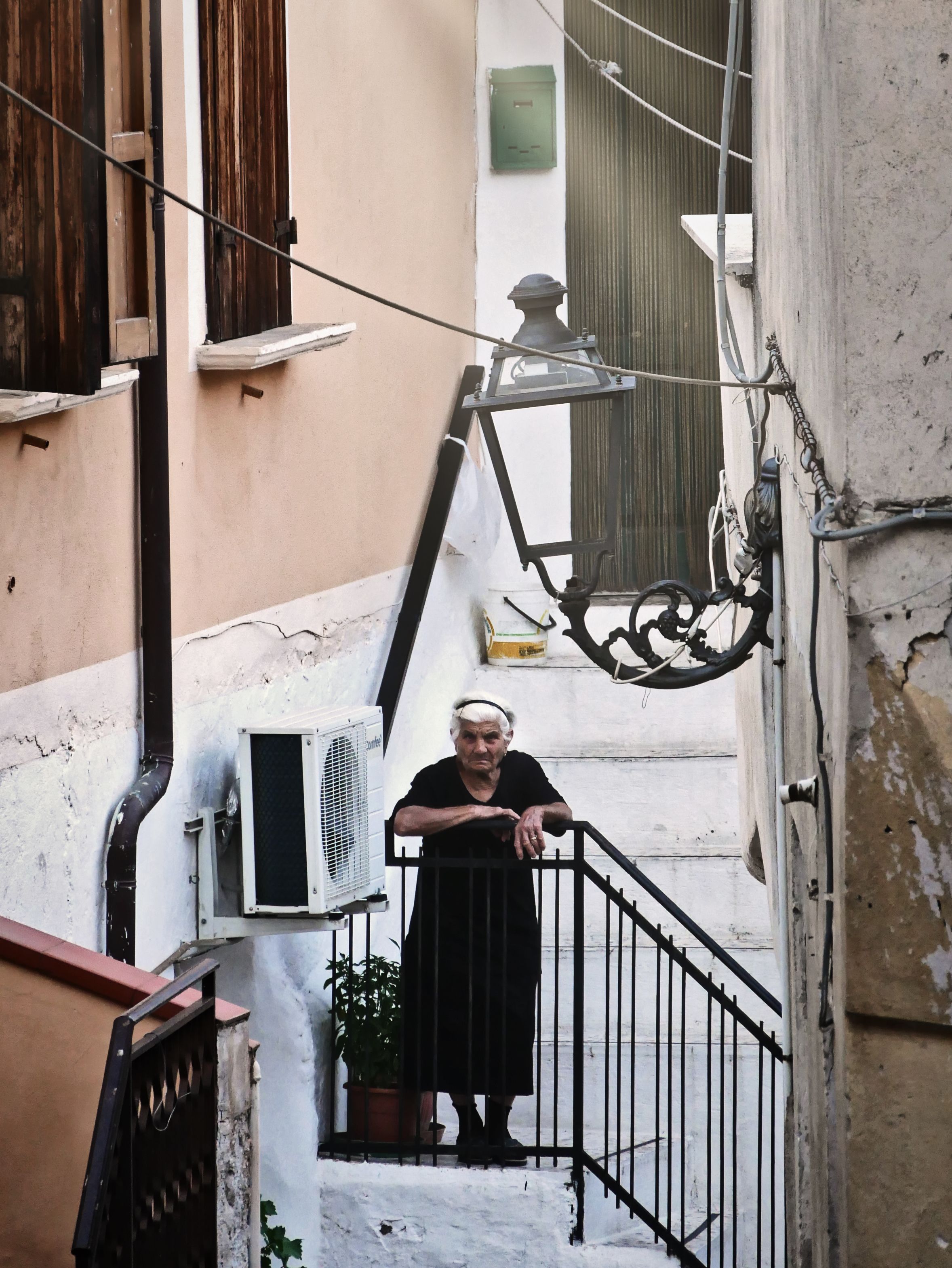 Elderly woman standing on rustic stairs in Calabria, Italy