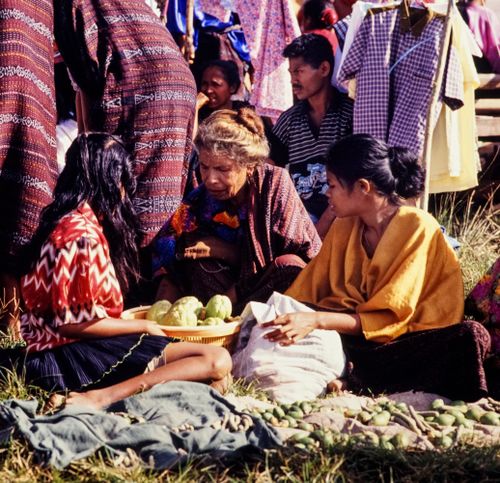 Free Local women in a vibrant Indonesian market selling fruits and traditional textiles. Stock Photo