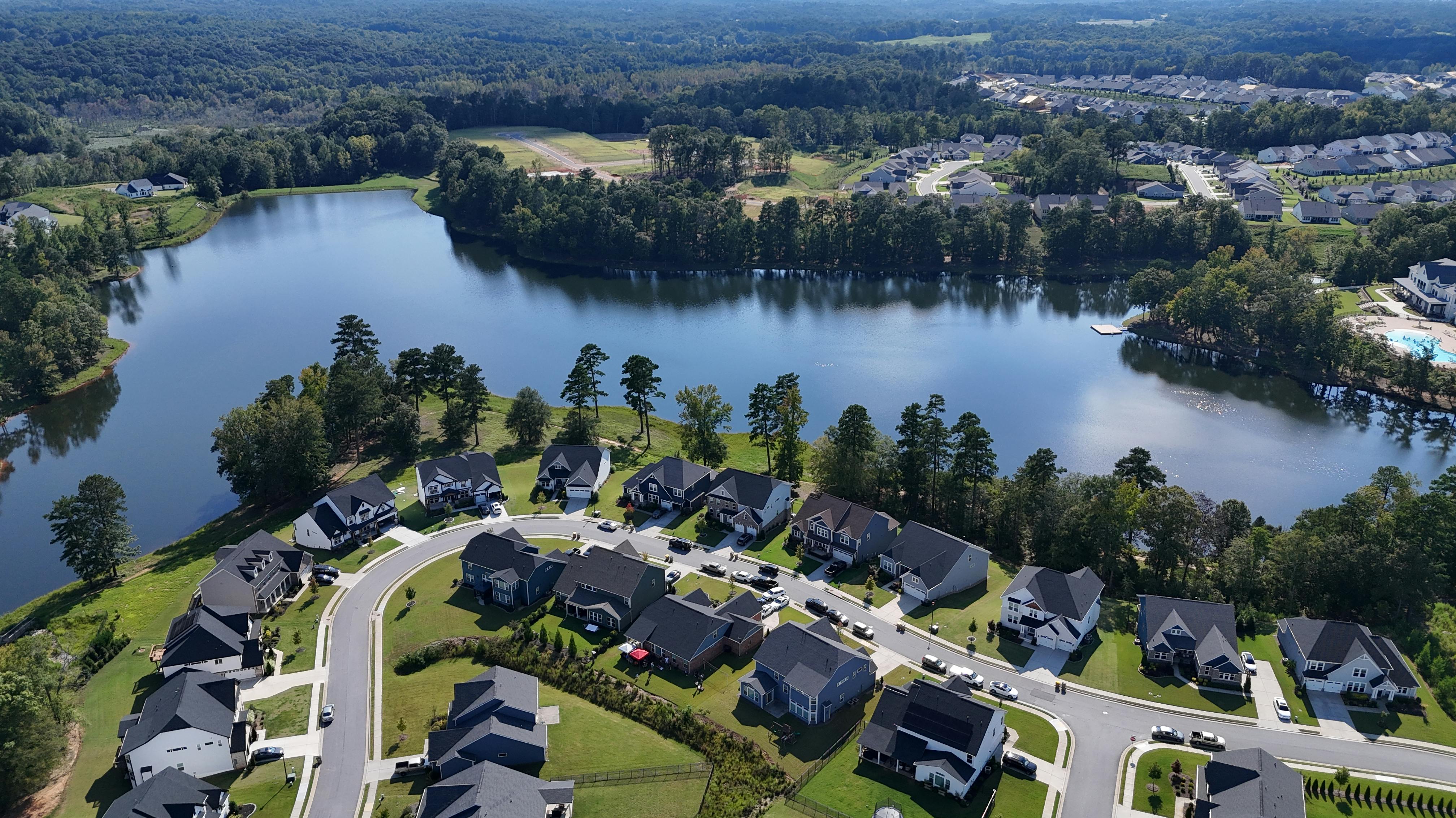 Aerial shot of a suburban neighborhood with a lake in Braselton, Georgia, surrounded by lush greenery.