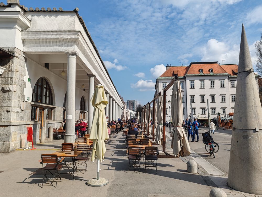 Colonada pieței centrale din Ljubljana, cu terase de cafenea și biciclete parcate