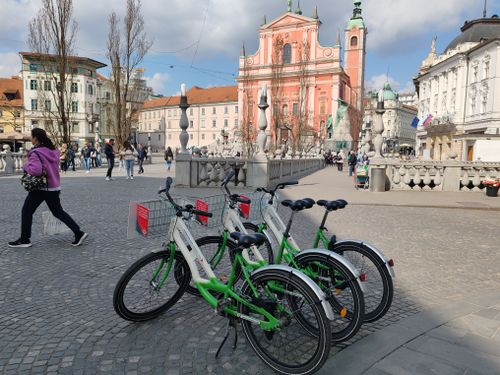 Free Green rental bicycles on a Ljubljana plaza with urban architecture. Stock Photo