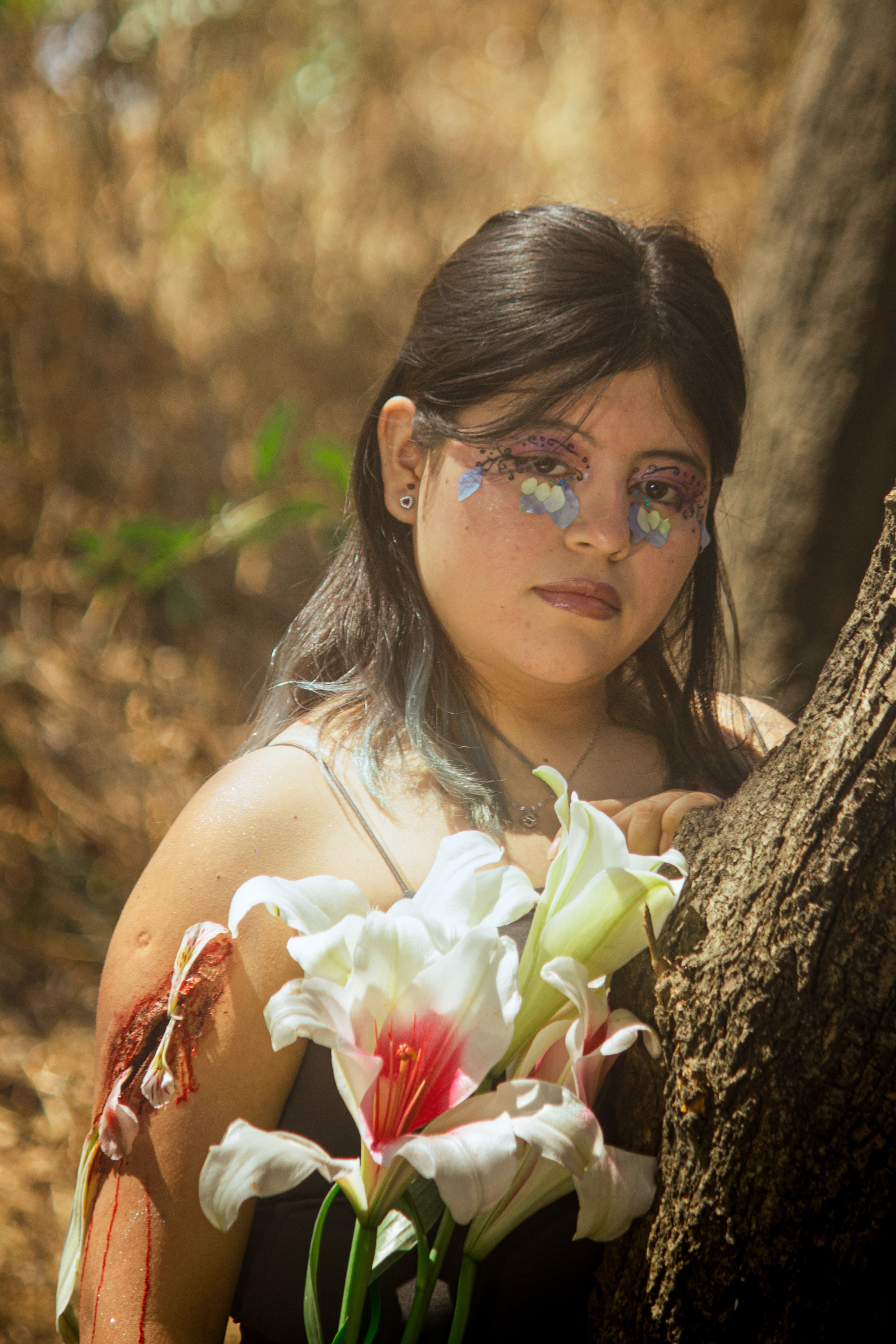 An artistic portrait featuring floral accessories and creative makeup in an outdoor park setting.