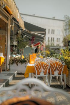Rustic outdoor café with colorful tables and chairs on a sunny day.