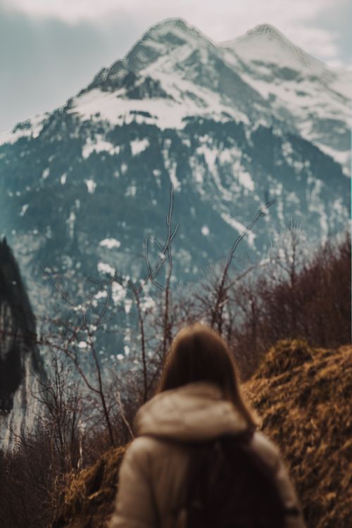Free A person stands on a trail, gazing at majestic snow-covered peaks in a serene winter scene. Stock Photo