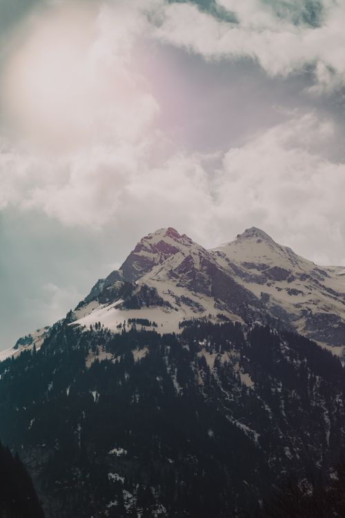Free Majestic view of snow-covered mountains under a cloudy sky in winter. Stock Photo