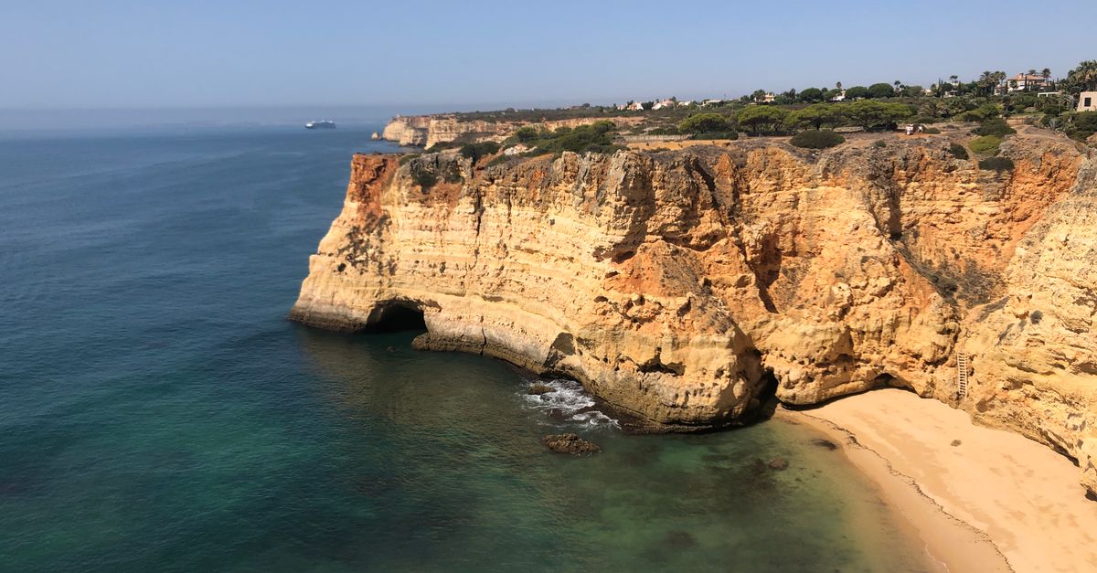 A breathtaking view of the Algarve coastline featuring dramatic cliffs and a serene beach in Portugal.