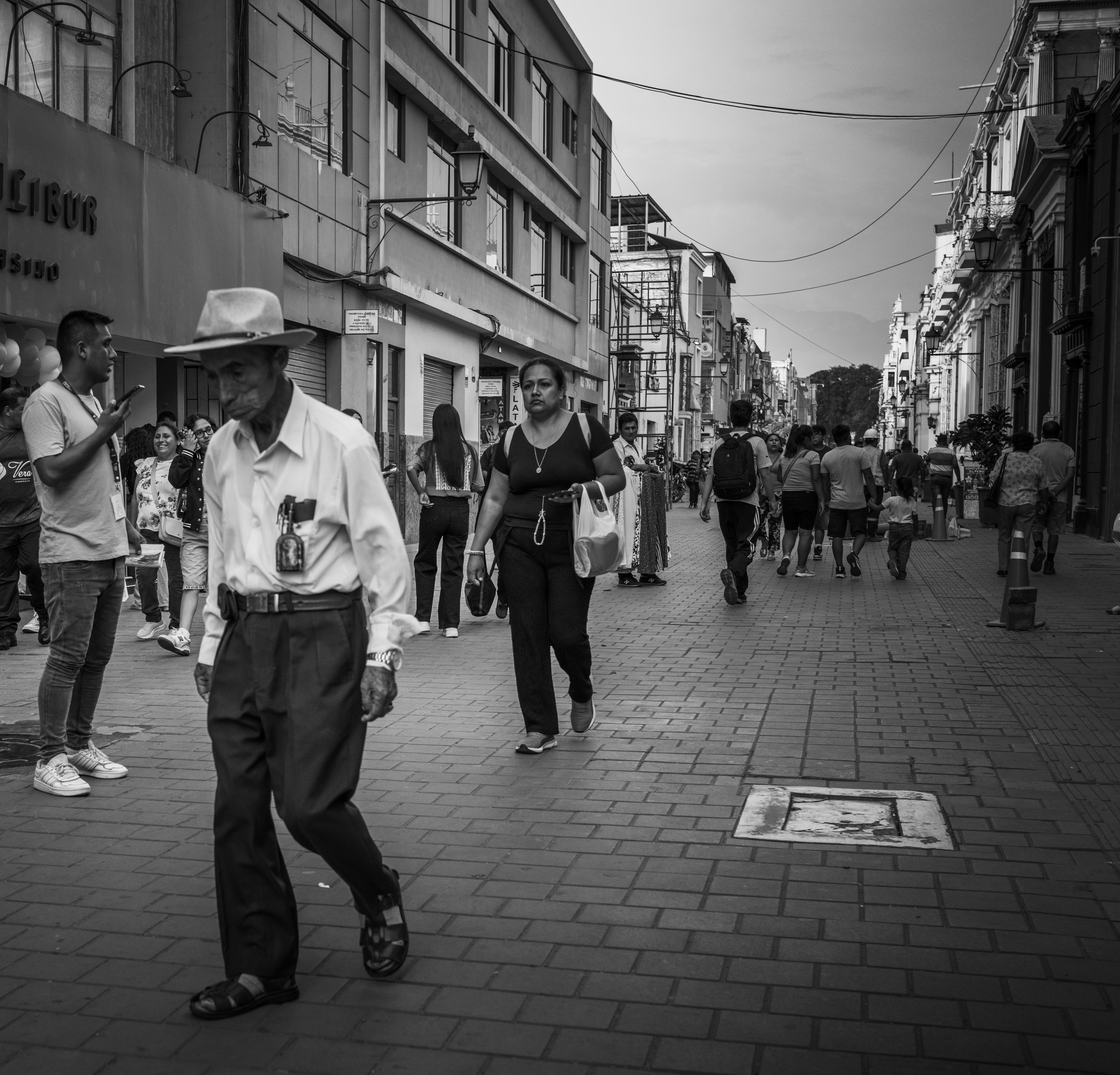 Busy street in Trujillo captured in black and white, showcasing diverse pedestrians.