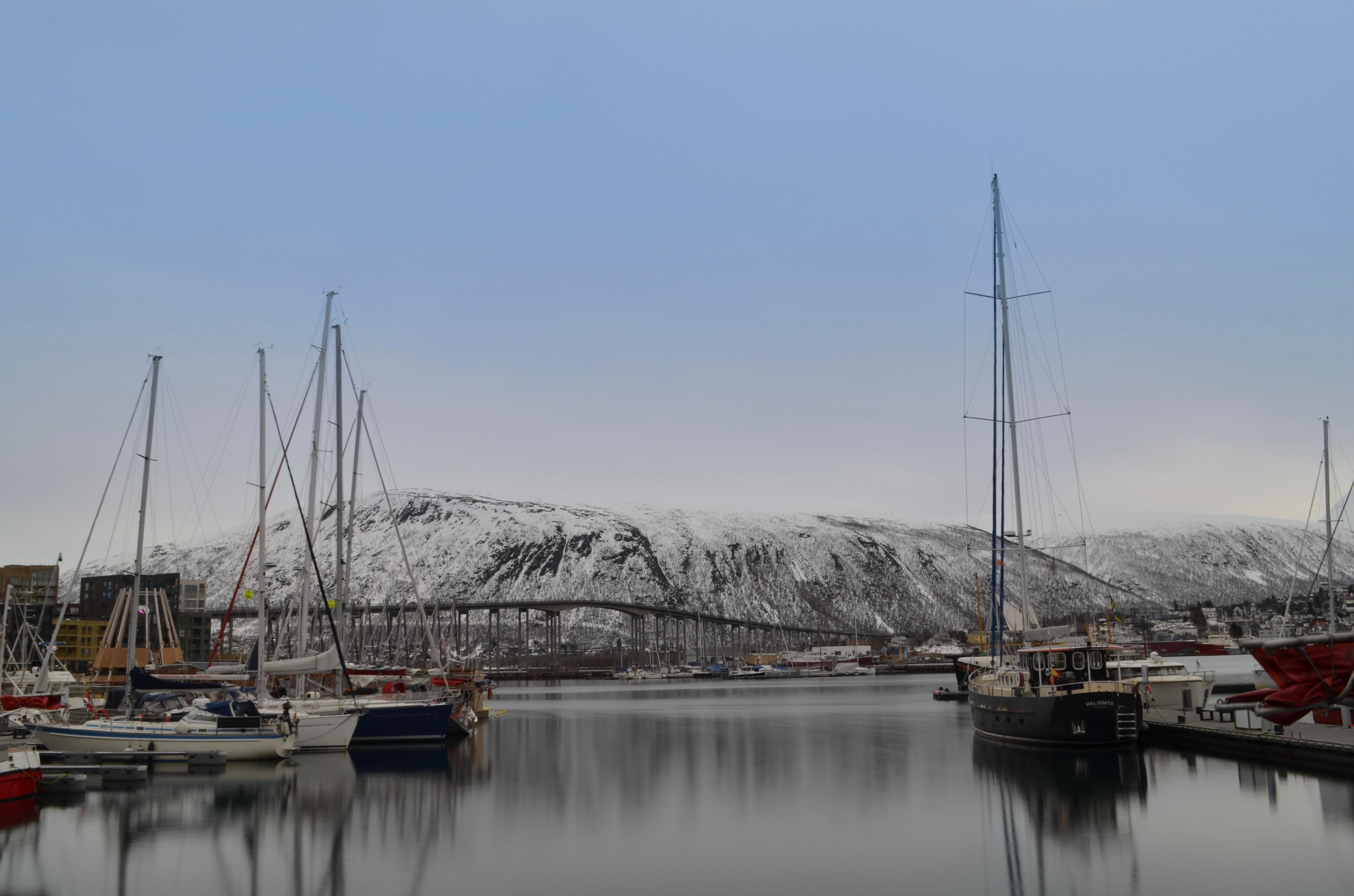 Boats moored in Tromso harbour with snow-covered mountains behind
