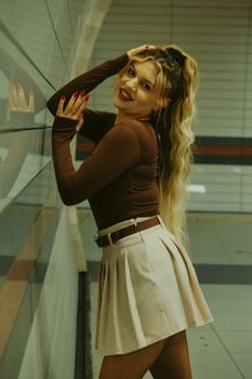 Fashionable woman with long hair poses in a modern subway setting. Urban style and elegance.