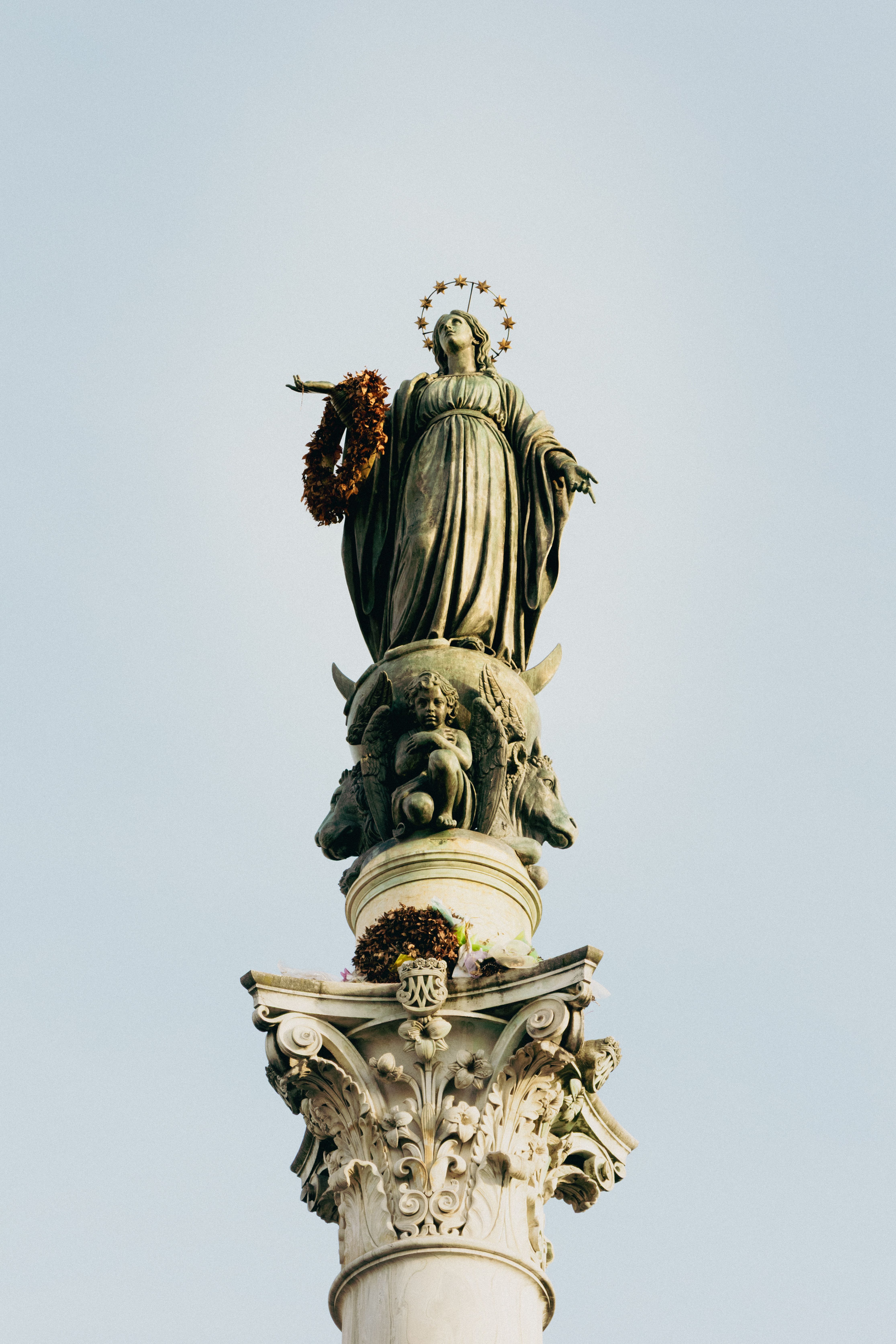 A stunning view of the Madonna statue on a Roman column against a clear sky.