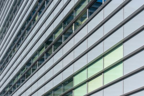 Free Detailed view of a modern building's glass facade with repeating windows and lines. Stock Photo