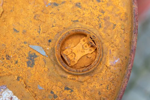 Detailed close-up of a rusty oil barrel with peeling orange paint texture.