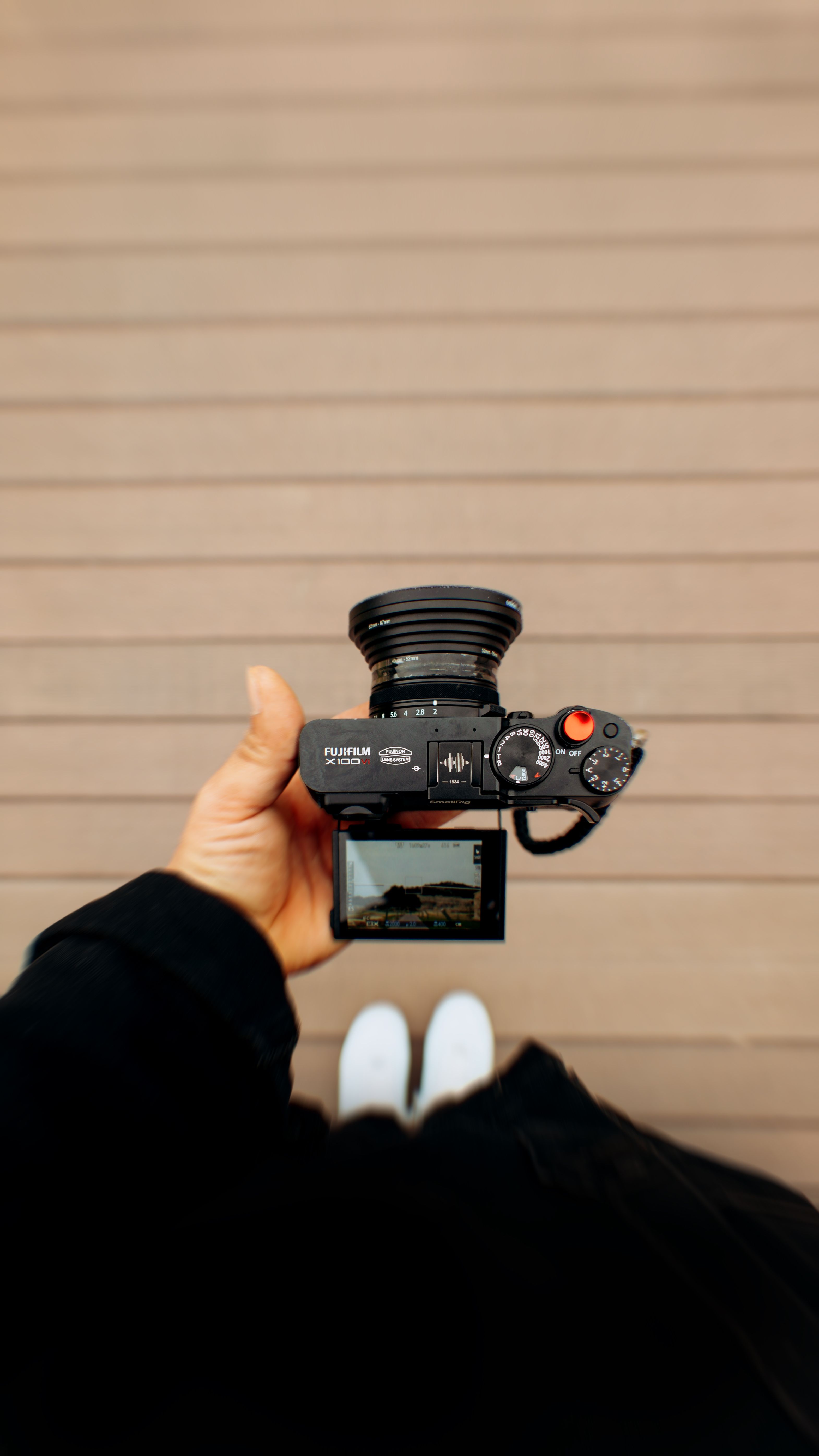 View from above of a person holding a camera over a wooden deck, showcasing photography perspective.