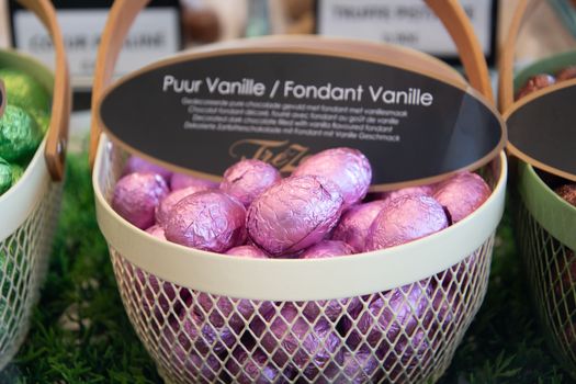 Basket of pastel pink foil wrapped chocolate eggs labeled 'Puur Vanille'. Ideal for Easter celebrations.