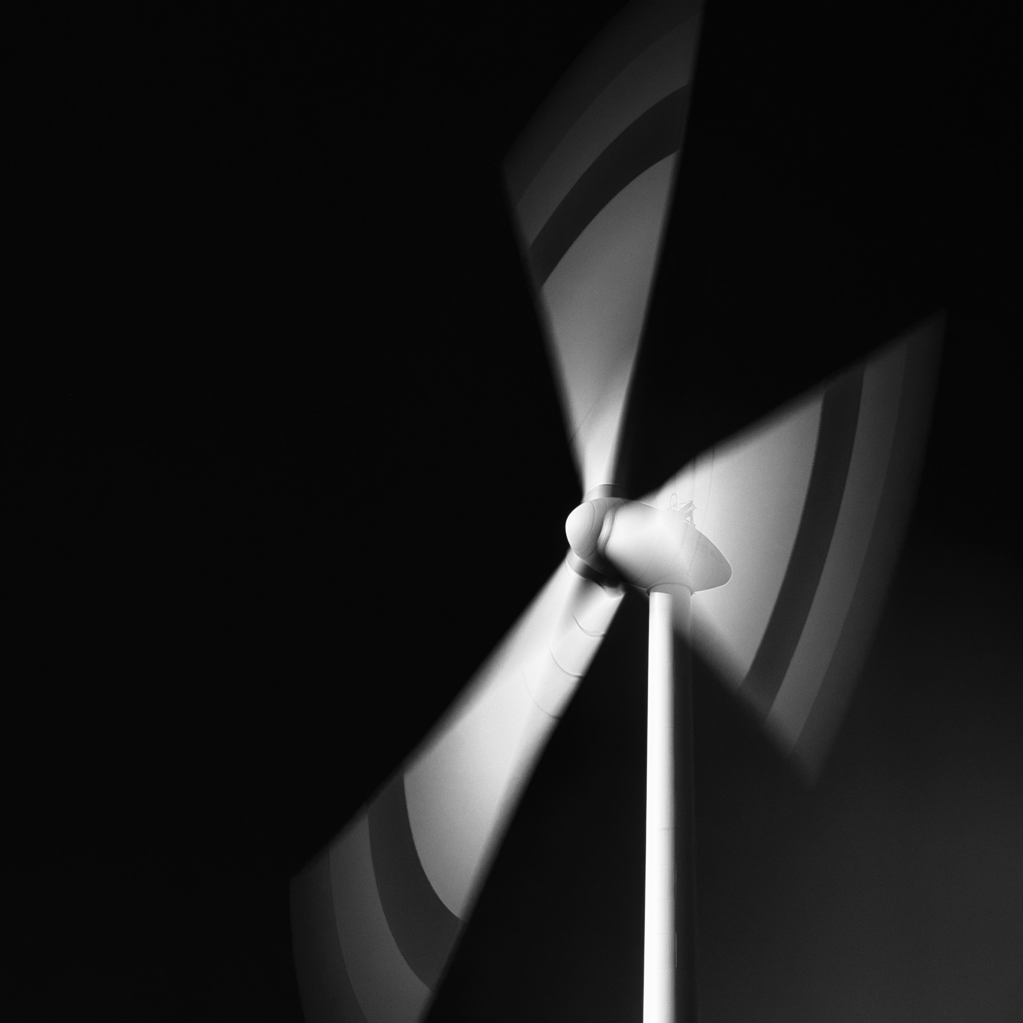 Artistic black and white photograph of a wind turbine in motion, capturing renewable energy themes.