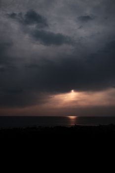 A stunning sunset over the ocean with dramatic clouds creating a serene atmosphere.