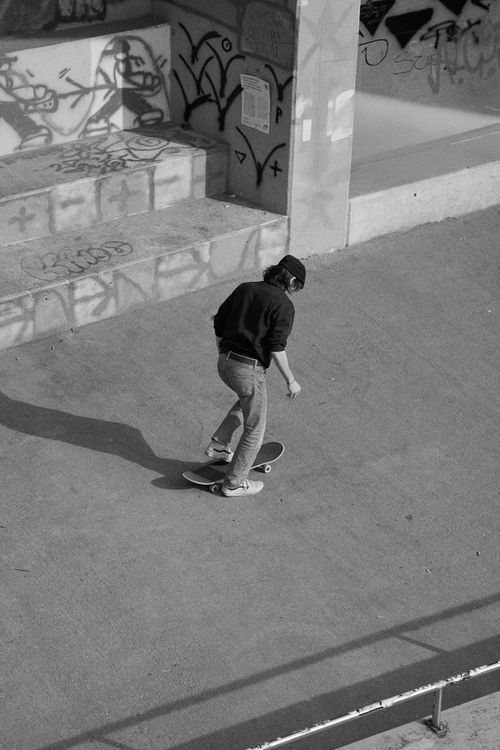Free Monochrome photo of a skateboarder in an urban setting with graffiti. Stock Photo