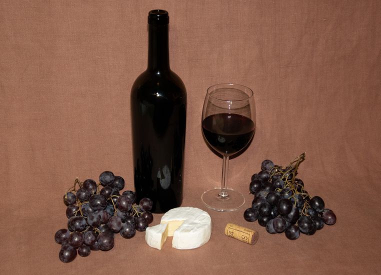 Cheese platter and grapes near wine glasses