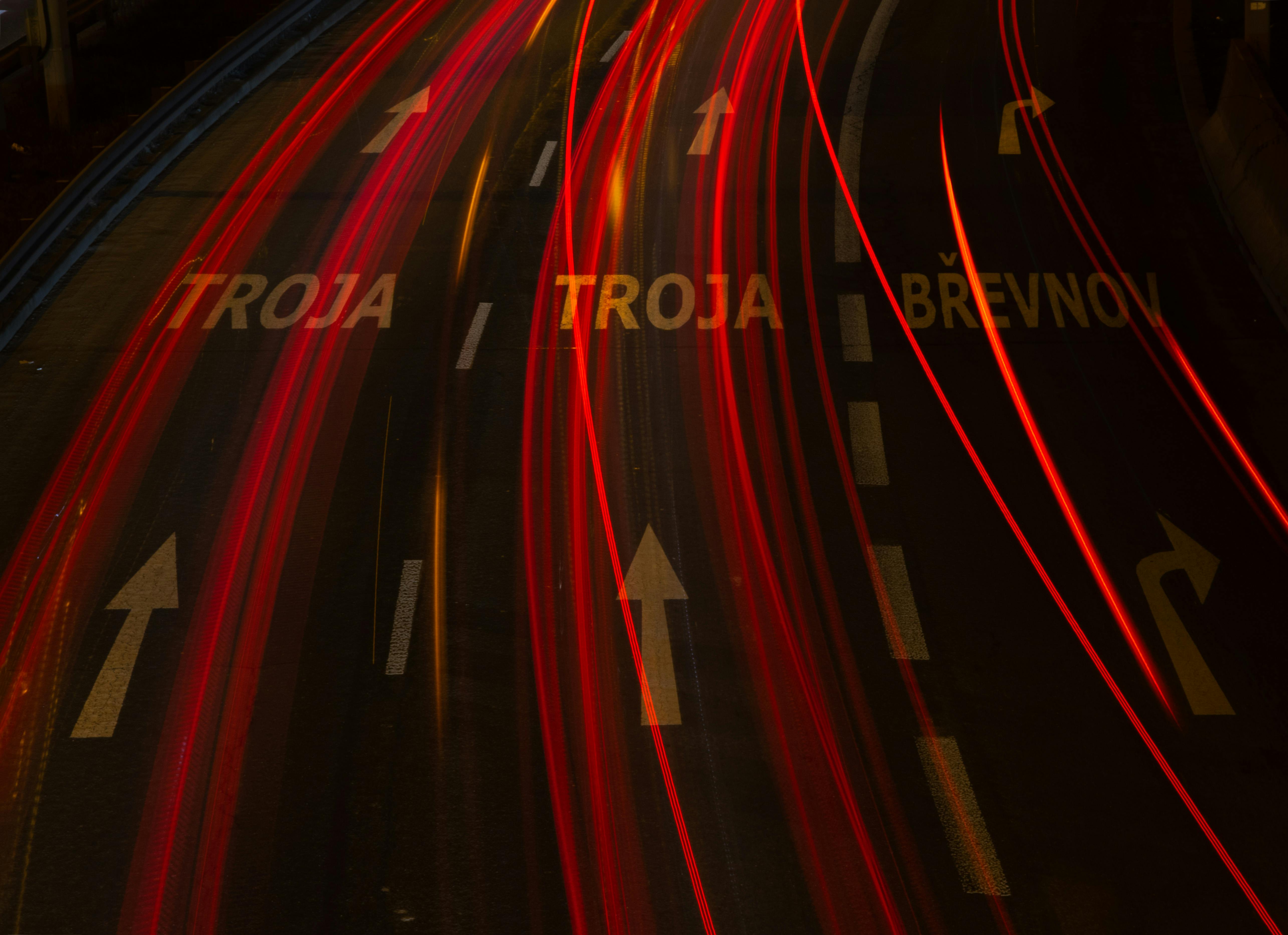 Long-exposure shot of urban highway with light trails and directional arrows, creating a dynamic night scene.