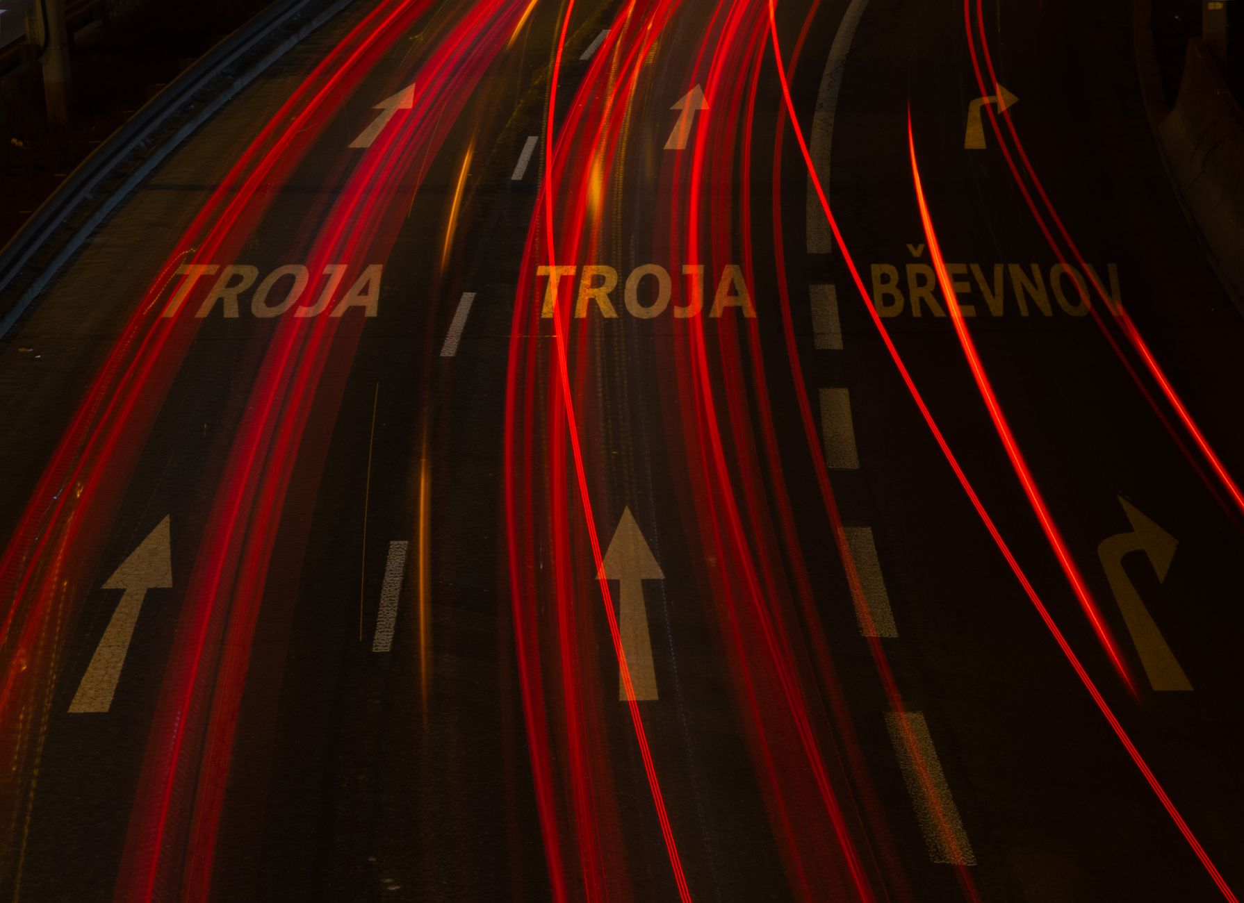 Long-exposure shot of urban highway with light trails and directional arrows, creating a dynamic night scene.