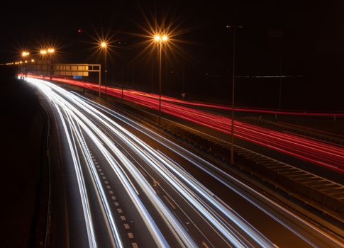 Captivating long exposure shot of a highway at night with vibrant light trails from passing vehicles.