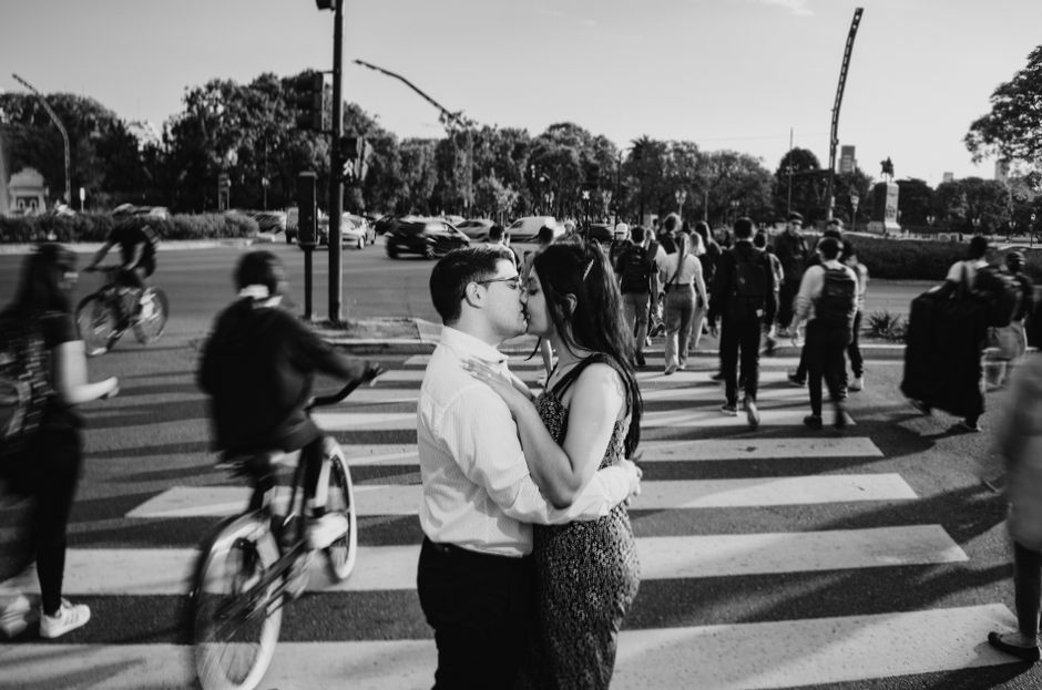 Black and white photo of a couple kissing on a bustling Buenos Aires crosswalk.