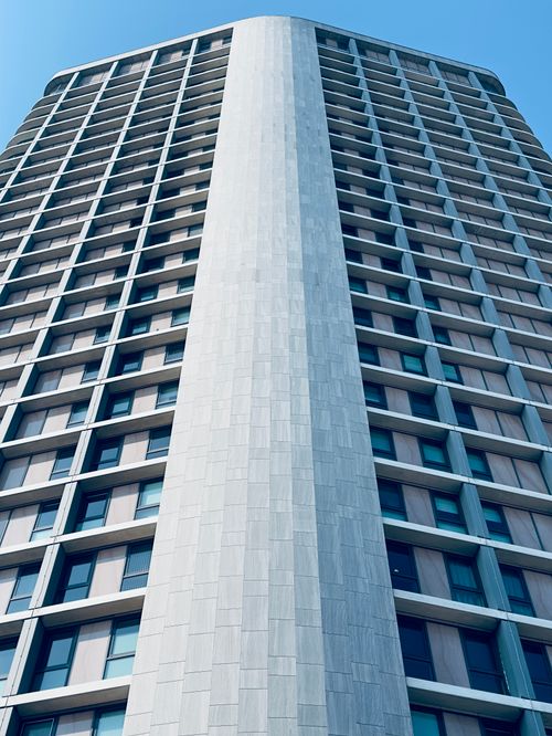 Free View of a contemporary skyscraper reaching into a clear blue sky, showcasing modern architecture. Stock Photo