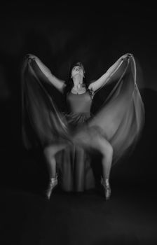 Graceful ballet dancer in motion with flowing dress captured in a dramatic black and white photo.