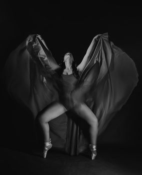 A graceful dancer in motion, captured in a dramatic black and white setting.