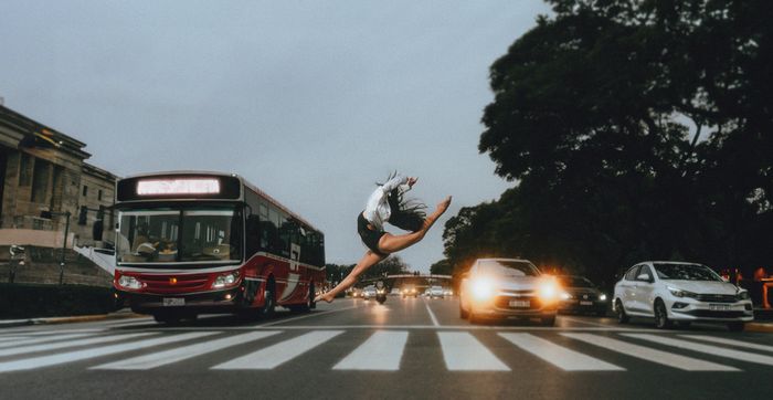Dancer leaping over a crossing in evening traffic &mdash; photo by Maive & Nahuel Fotograf&iacute;a on Pexels