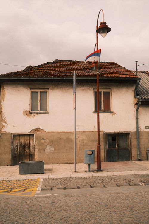 Free Old European house exterior with flag and street lamp on a cloudy day. Stock Photo