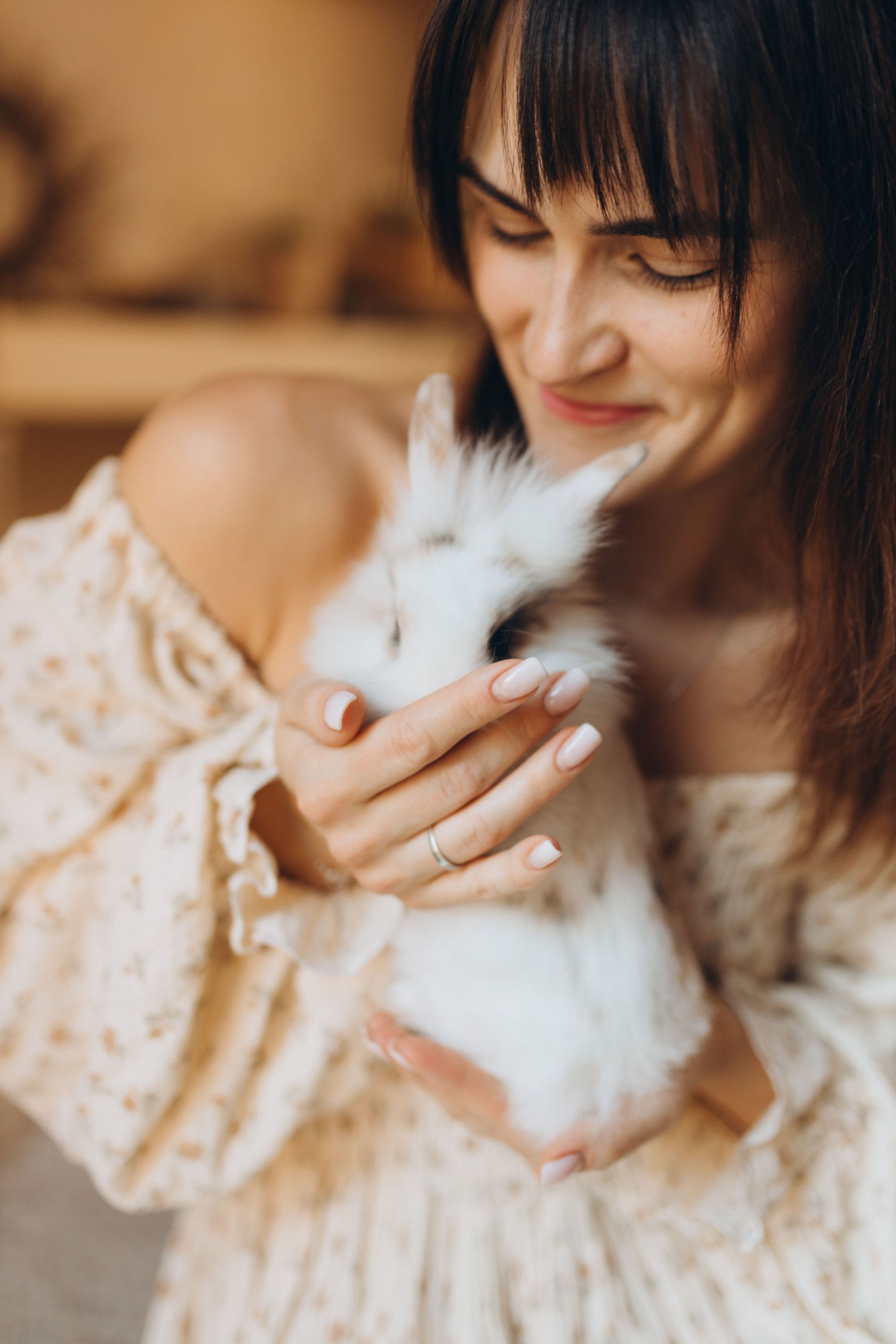 Woman Gently Holding Fluffy White Rabbit Indoors · Free Stock Photo