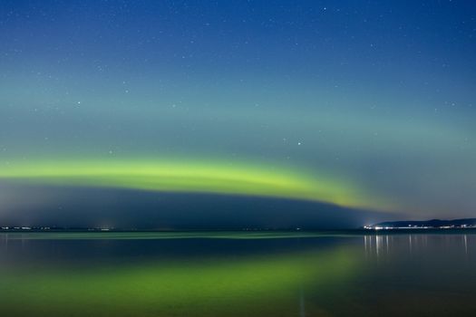 Captivating northern lights reflecting on a tranquil lake in Jönköping, Sweden, under a starlit night sky.