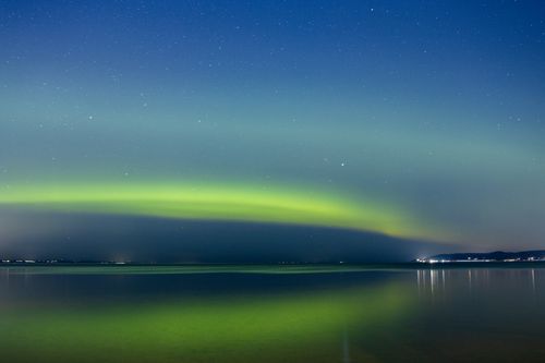 Free Captivating northern lights reflecting on a tranquil lake in Jönköping, Sweden, under a starlit night sky. Stock Photo