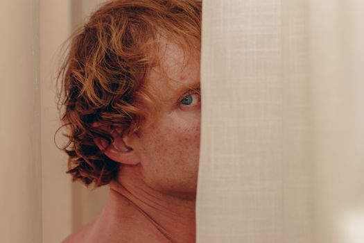 A person peeking out from behind a curtain, creating a sense of mystery and intrigue.