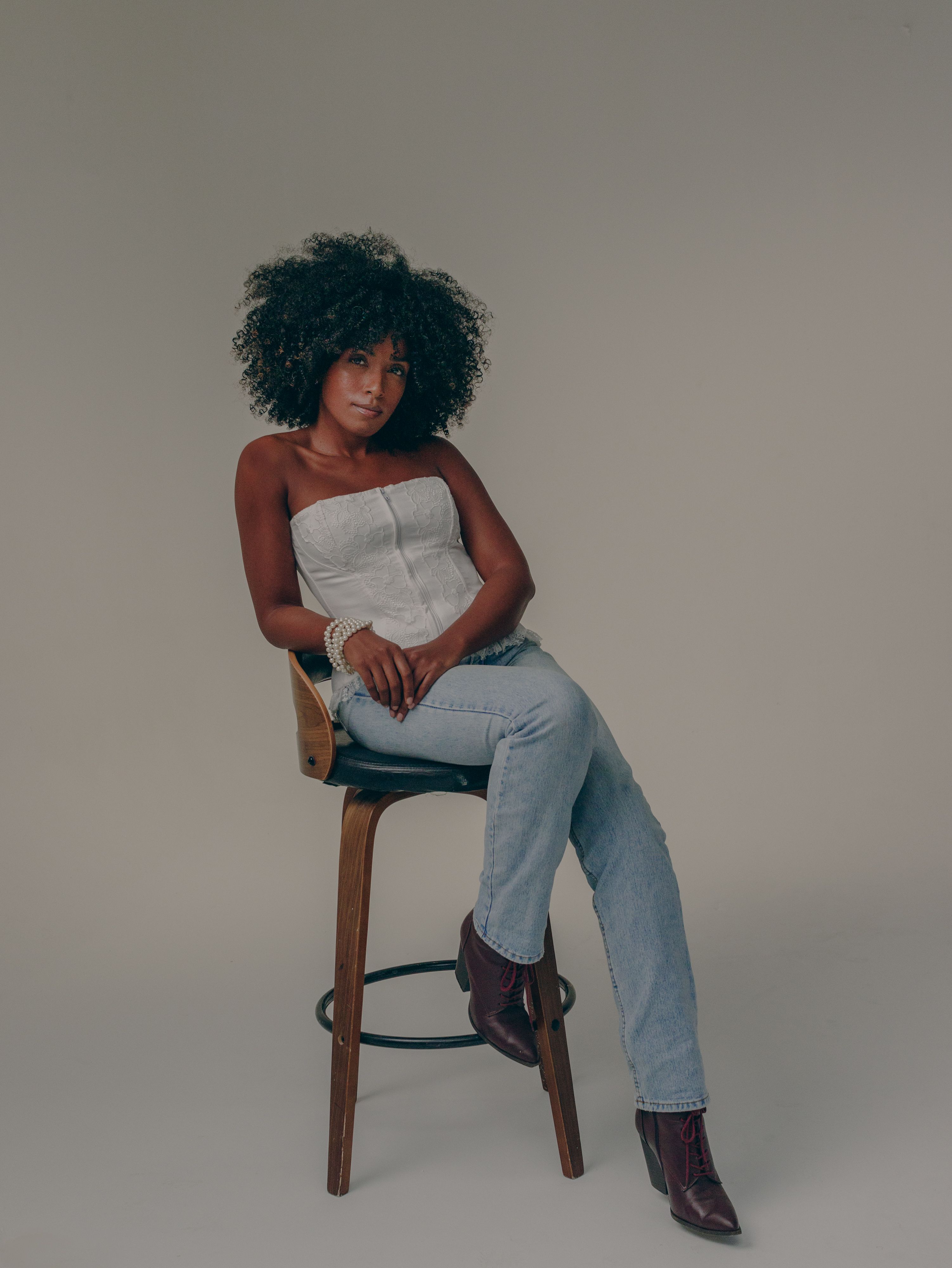 Stylish Woman Posing on Stool in Studio Setting · Free Stock Photo