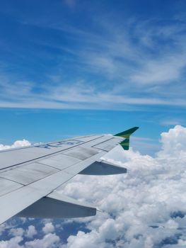 A view from an airplane window showing the wing and a beautiful blue sky above the clouds.