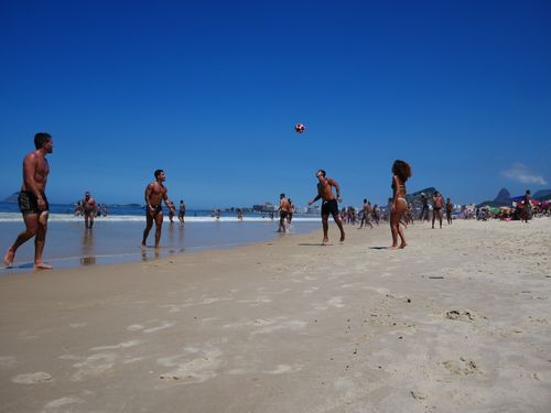 Free People playing soccer on Ipanema Beach, Rio de Janeiro under clear blue skies. Stock Photo