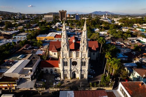 Free Aerial view of El Rosario Church in San Salvador, showcasing its stunning architecture amidst urban surroundings. Stock Photo