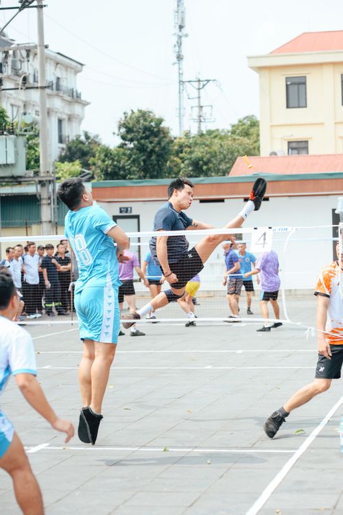Free Energetic scene of people playing foot volleyball on an outdoor court with spectators. Stock Photo