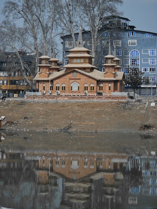 Free A serene view of a historic riverside building reflecting in the water. Stock Photo