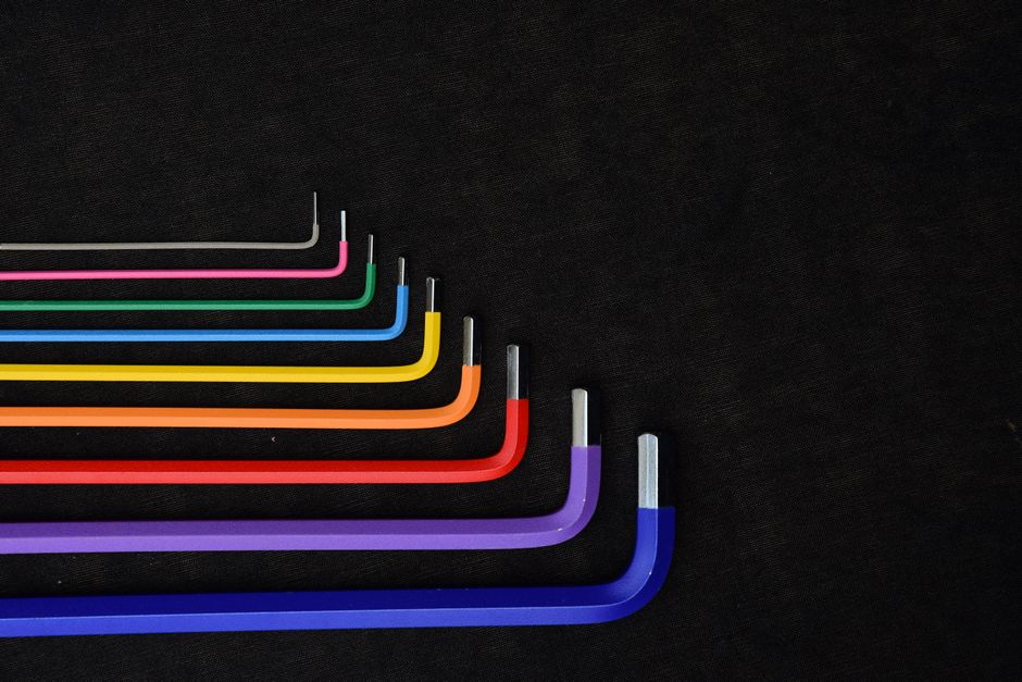 Set of colorful L-shaped hex keys displayed in a row on a dark textured background.