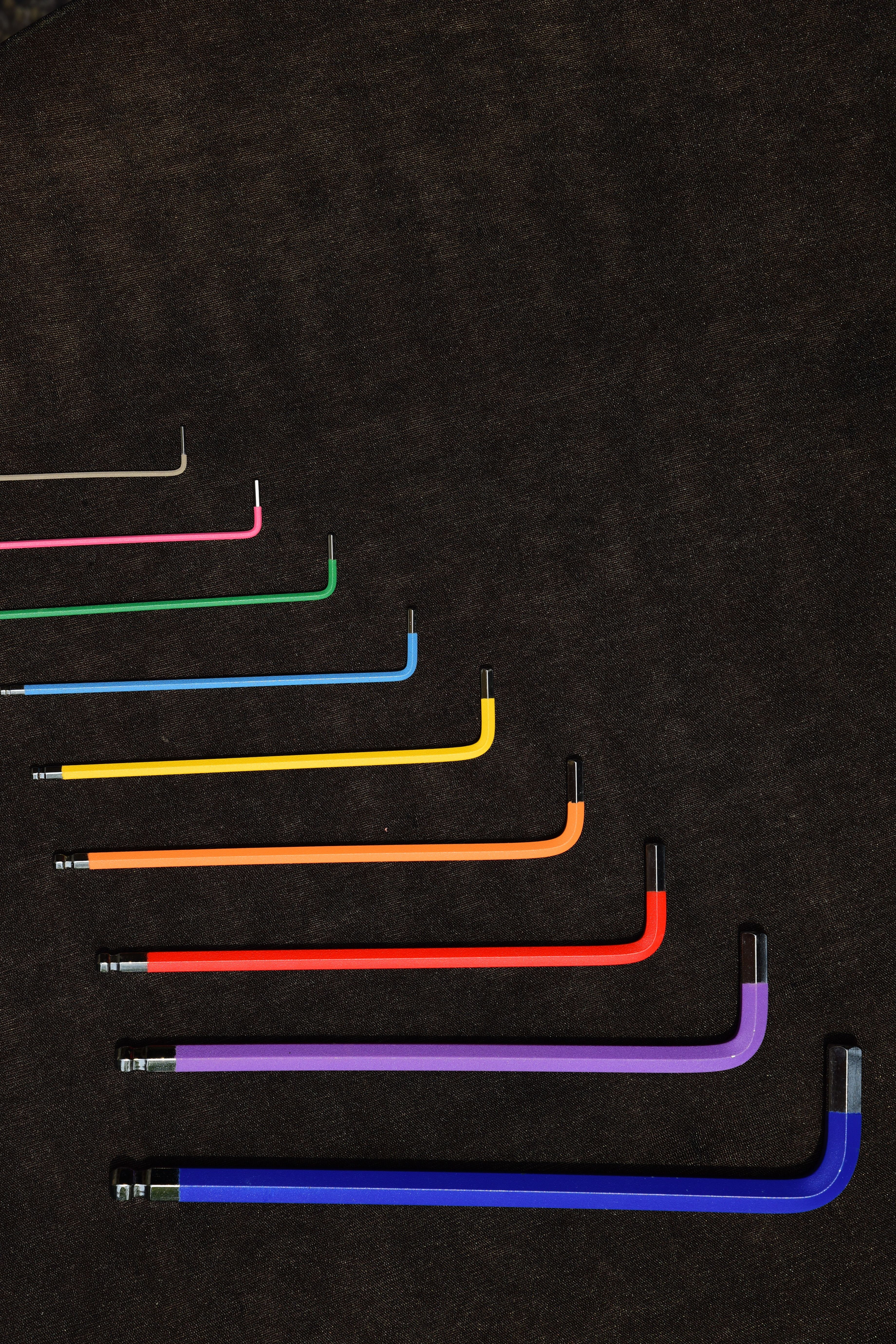 Vibrant multicolored hex keys arranged on a textured dark surface.