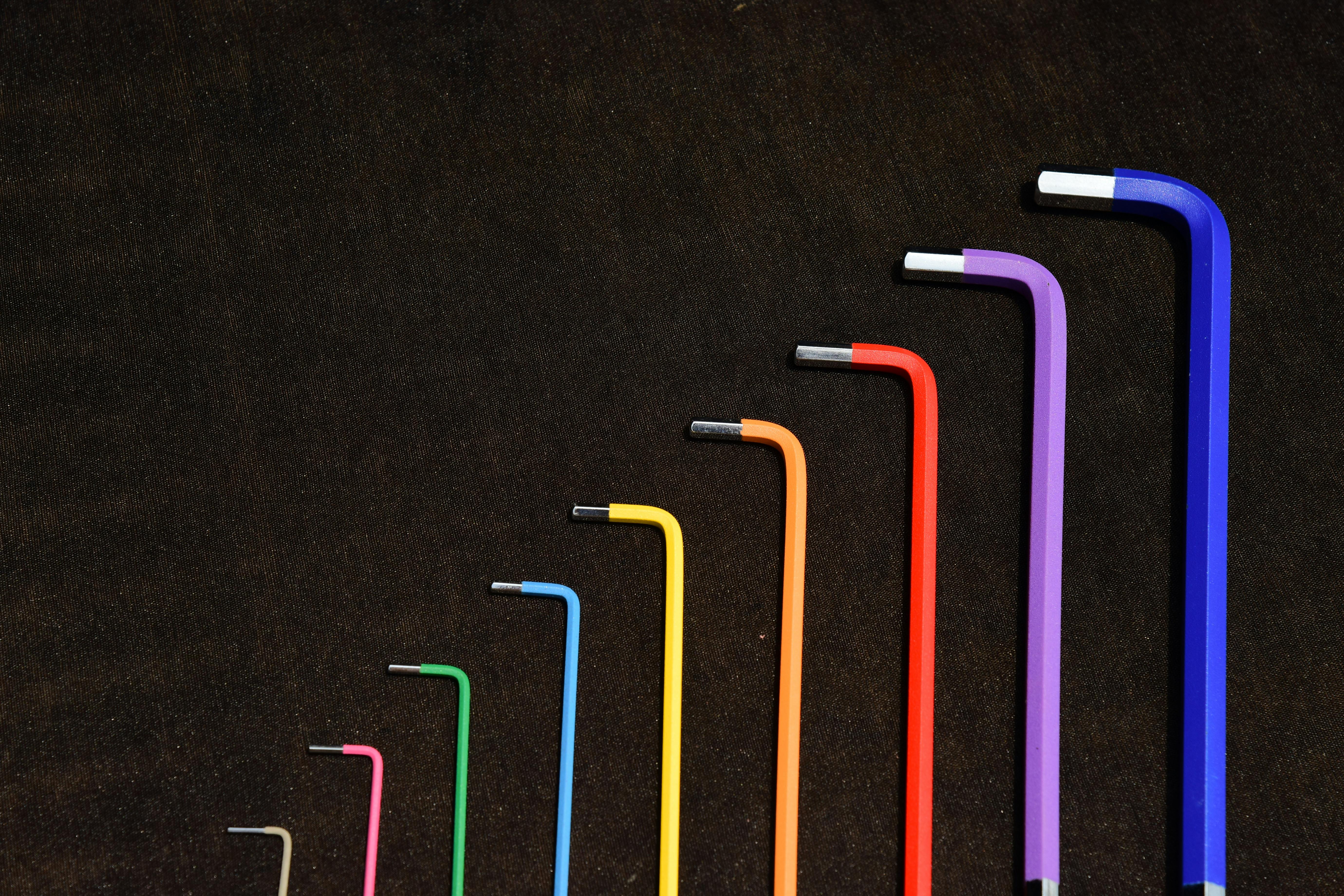 A set of colorful Allen wrenches organized from small to large on a dark background.