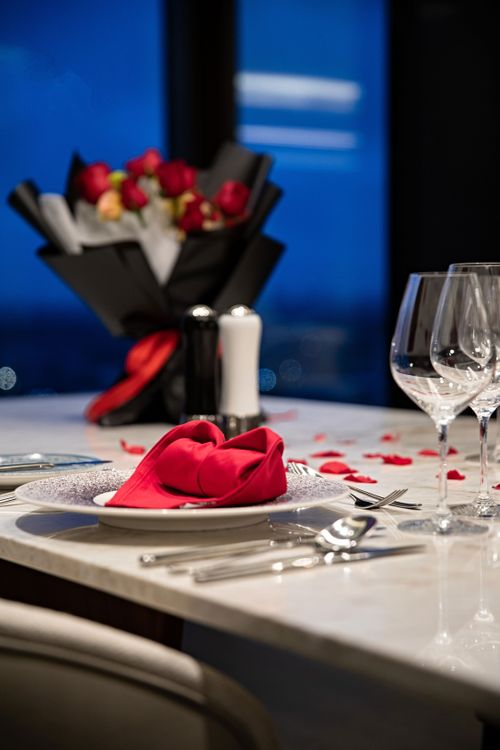 Free Beautifully arranged dinner table with red roses and elegant dinnerware for a romantic evening. Stock Photo